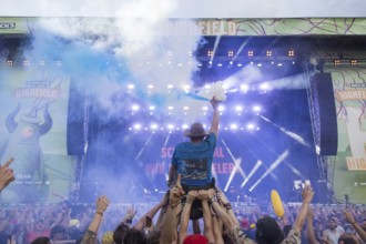 A wheelchair user with pyro in his hand is carried over the audience during the performance of the