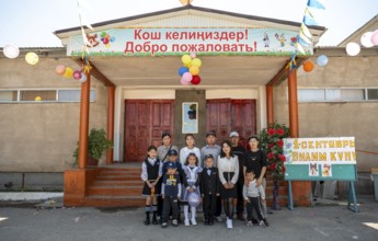 Family and school children, group posing in front of the school on the first day of school,