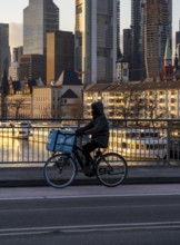 Skyline of the city centre of Frankfurt am Main, cyclist on the Alte Brücke, Wolt delivery service,