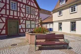 Running fountain with flowering geraniums and bench in Michelstadt, Odenwald, Odenwaldkreis, Hesse,