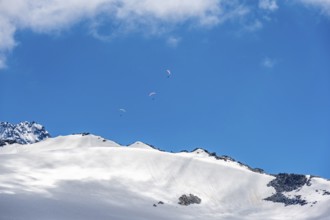 Paraglider in front of blue sky over mountain landscape, glacier Glacier du Tour, high alpine