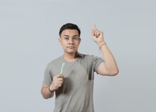 Handsome guy holding toothbrush pointing an advertisement up. Caucasian handsome man holding