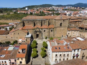 Large historic church with wide steps and surrounded by old buildings with red roofs in a hilly