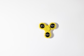 A yellow fidget spinner in motion, on a white background