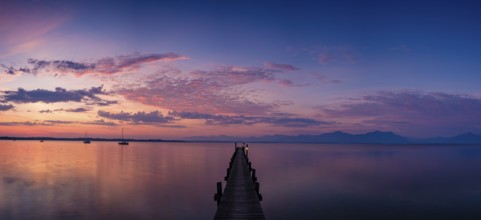 Panoramic photo, Illuminated clouds over sailing boats and jetty on Lake Chiemsee at dawn, behind