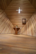 Modern interior of a wooden church with an altar table, flowers and a cross, minimalist design,