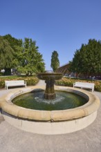 Fountain with benches, graduation tower and trees in the rose garden park in Bad Salzuflen, Lippe