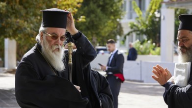 Archbishop Amphilochios, Orthodox priest with staff in hand, outside in a crowd of people in