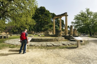 Hiker, tourist at the Philippeion, restored ruins, rotunda, ancient Olympia in spring,