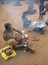 Sri Lankan woman, 63 years old, frying traditional doughnuts on a fire on the ground, Sella