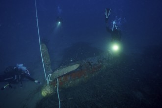 Divers illuminate an aircraft wreck from the Second World War during an underwater exploration,