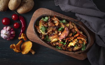 Fried chanterelles with potatoes, in a clay frying pan, top view, homemade, no people