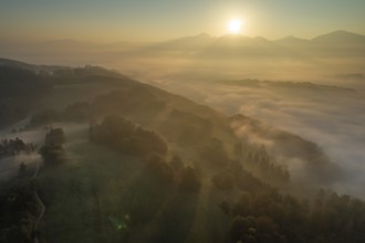 Aerial view of a mountain landscape over clouds, fog, backlight, morning light, view of Kochler