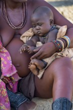 Baby in the arms of a Himba woman, traditional Himba village, Kaokoveld, Kunene, Namibia, Africa