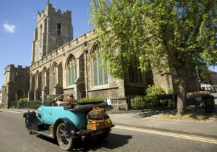 Classic veteran car passing Church of Saint Peter, Sudbury, Suffolk, England, United Kingdom,