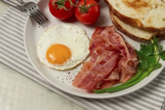 Breakfast, fried egg, bacon and bread, with cherry, on a light background, homemade, no people