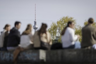 People sitting in the sun on the banks of the Spree in Berlin, 27 March 2024, with the Berlin