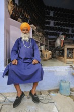 Man in traditional dress in front of a shoe shop, Bharatpur, Rajasthan, India, Asia