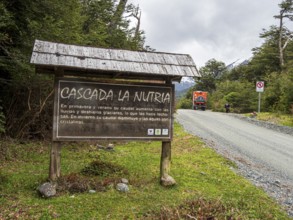 Information board at waterfall Cascada La Nutria, overlander truck on gravel road, Valle