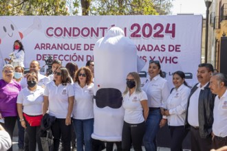 Oaxaca, Mexico, Health workers pose for photos with a person wearing a condom costume as part of