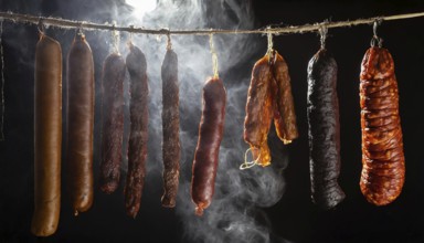 Food, various smoked sausages hanging on a string next to each other in the smoker, AI generated,