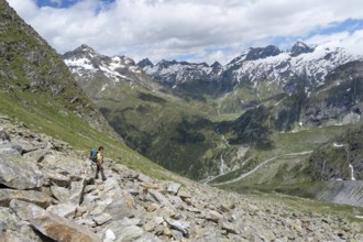 Mountaineer on a hiking trail in front of a picturesque mountain landscape, rocky mountain peaks