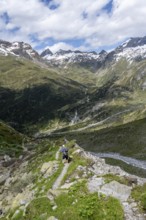 Mountaineer on hiking trail in front of picturesque mountain landscape, rocky mountain peaks with