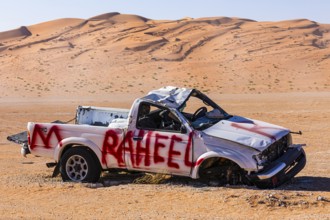 Car wreck, left behind in the Rub al Khali desert, sand dunes sculpted by the wind, Dhofar