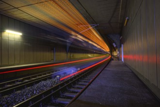 A train races through a tunnel, creating bright streaks of light and conveying a sense of speed,