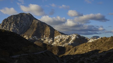 Houses of a village stretch up a barren mountain, illuminated by the rising sun, Colourful mountain