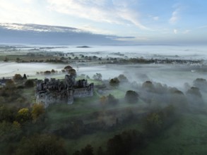 Raglan Castle in the fog at dawn from a drone, Monmouthshire, Wales, England, United Kingdom,