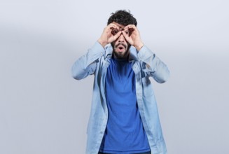 Curious man making binoculars gesture isolated. Guy making binoculars gesture isolated. Man making