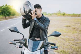 Male biker on motorcycle putting on safety helmet. Biker motorcycle safety concept, Young