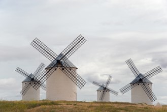 Historic windmills with a cloudy atmosphere. The white colour of the mills contrasts with the grey