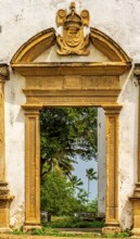 Baroque church portal overlooking tropical vegetation and ruins in the city of Olinda in