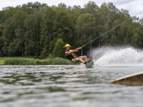 Sporty man with wakeboard, water sports, water skiing and wake park