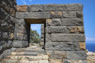 Ancient ruined wall with an archway in an arid landscape overlooking the sea, Palaiokastro, Ancient