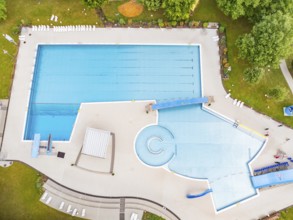 Aerial view of an outdoor swimming pool with a large swimming pool and water slide, surrounded by