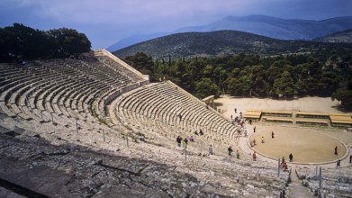 People explore the extensive ruins of an ancient amphitheatre with mountain views, Ancient