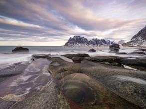 Rocks at Utakleiv beach with rock formation Eye of Utakleiv, or Dragon's Eye, in a dramatic cloudy