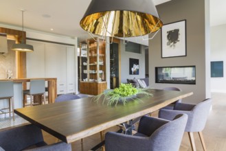 Chrome and walnut wood table with charcoal linen armchairs and large black and gold industrial