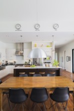 Open-concept dining and kitchen area with antique dining table with black leather and plastic