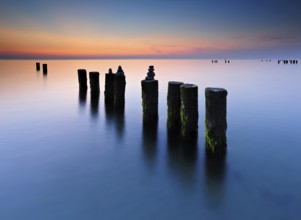 Stone pyramids on old groynes with algae in the water on the beach of the Baltic Sea, long exposure