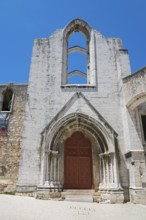 A Gothic church ruin with ornate archways standing out against the clear blue sky, Convento do