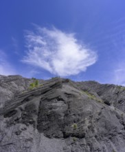 Dark slate and white cloud against a blue sky, Entraunes, Département Alpes-Maritimes, France,