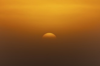 A foggy sky penetrated by an orange-coloured sunset creates a dense atmosphere, sunrise near