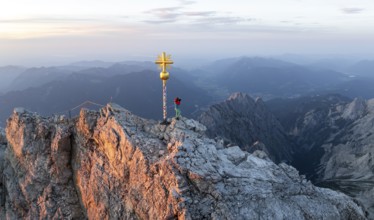 Woman photographing sunset, aerial view, Zugspitze and summit cross, high mountains, Bavaria,