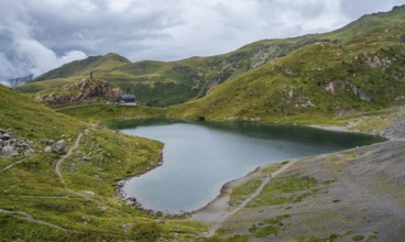 View of Wolayersee and Alpine Club hut Wolayerseehütte, cloudy mountain landscape, Carnic Alps,