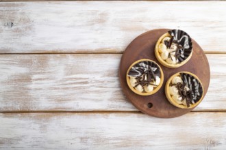 Sweet tartlets with chocolate and cheese cream on a white wooden background. top view, flat lay,