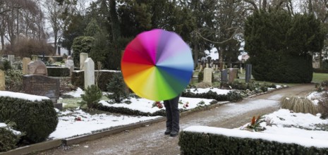 Man with colourful umbrella in grey weather between graves, Riesa cemetery, Saxony, Germany, Europe